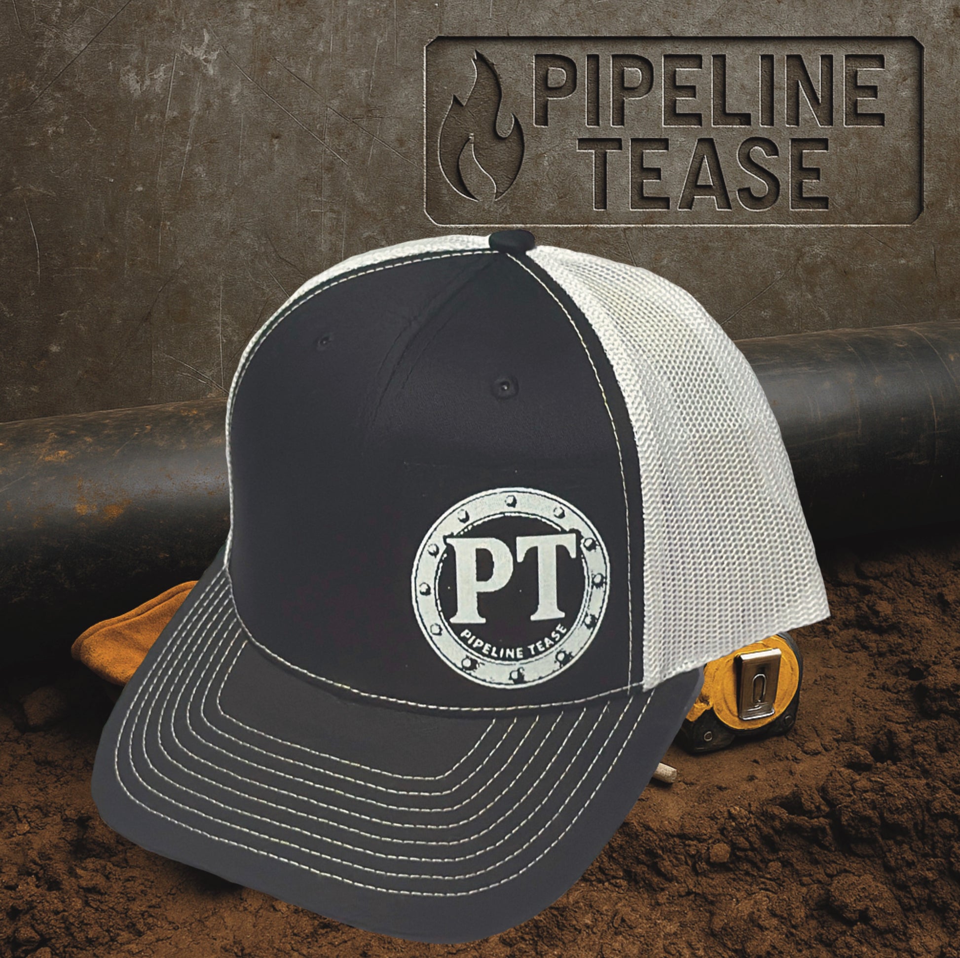 Black and white trucker hat featuring the Pipeline Tease white PT Flange logo, displayed on a dirt jobsite background with Pipeline Tease branding.