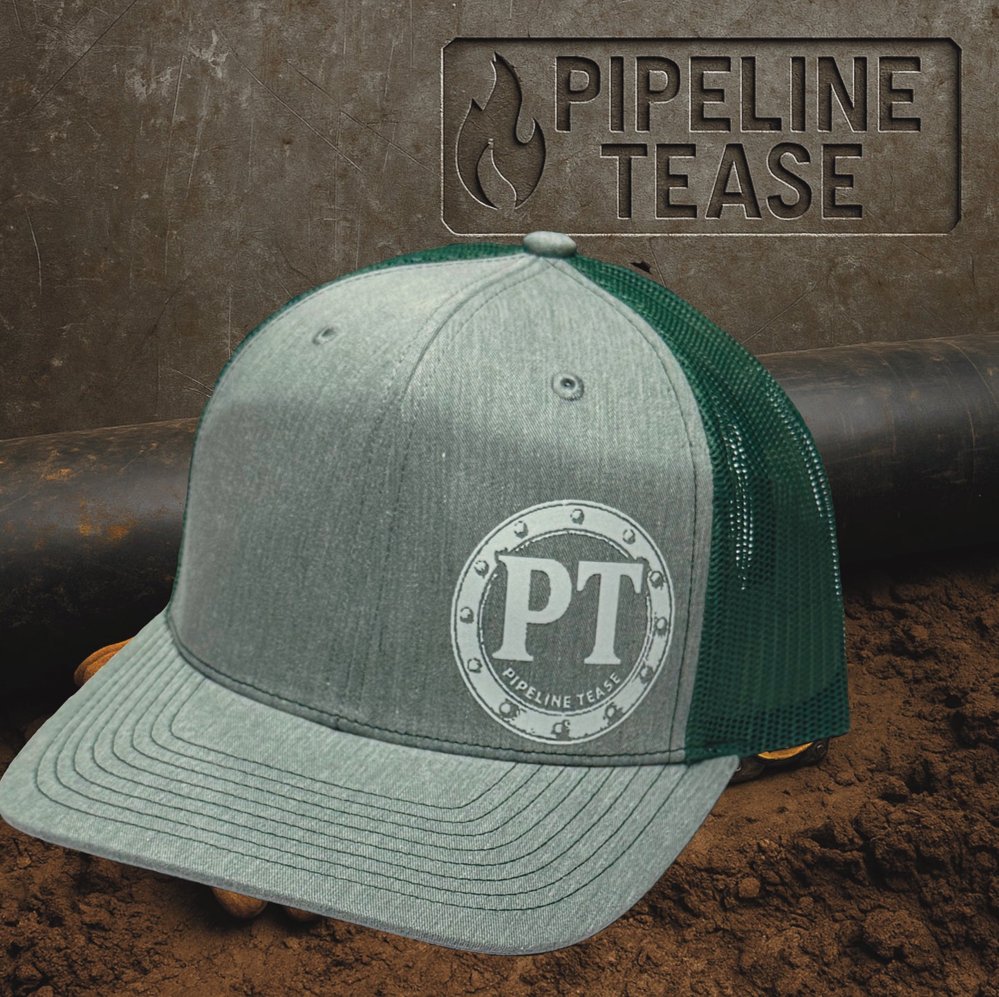 Heather grey and green trucker hat featuring the Pipeline Tease white PT Flange logo, displayed on a dirt jobsite background with Pipeline Tease branding.